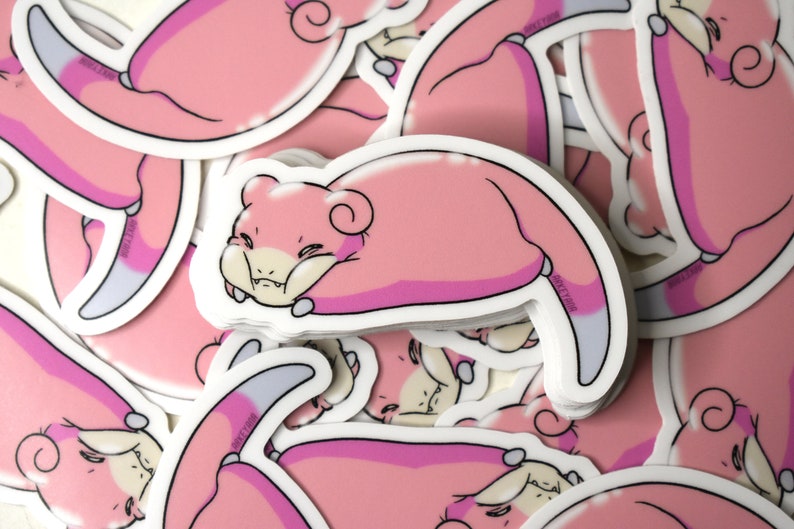 Puede incluir: Una pila de pegatinas rosas y blancas con una criatura rosa de dibujos animados con una cola enroscada. La criatura est&aacute; representada con una expresi&oacute;n gru&ntilde;ona y est&aacute; tumbada de lado.