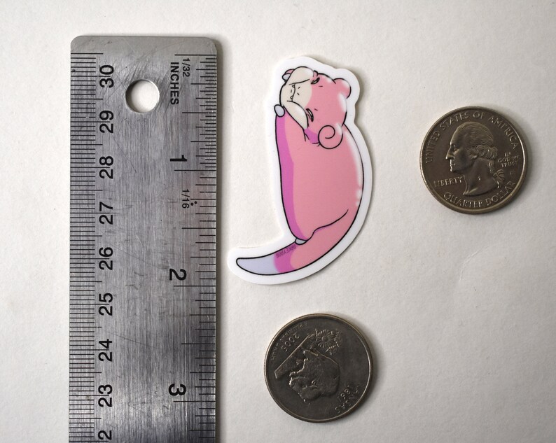 Puede incluir: Una pegatina de personaje de dibujos animados rosa y blanco de una criatura enroscada con cola. La pegatina mide aproximadamente 5 cm de alto.