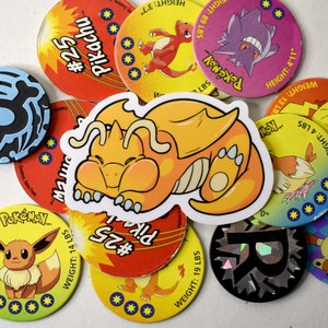 K&ouml;nnte beinhalten: Eine Sammlung von bunten Pok&eacute;mon-Sammelkarten mit verschiedenen Charakteren, darunter Pikachu, Glurak und Bisasam. Die Karten sind rund und haben einen gelben Hintergrund mit schwarzem Text und Bildern. Die Karten liegen auf einem wei&szlig;en Untergrund in einem Stapel.