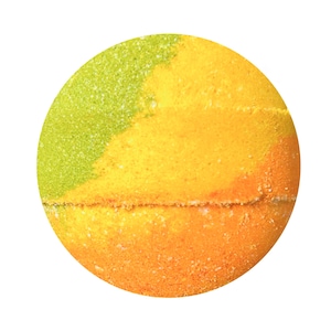 May include: A round bath bomb with a gradient of colors. The top left is green, transitioning to yellow, and then to orange at the bottom. The bath bomb has a textured, granular appearance, with a white line separating the colors.