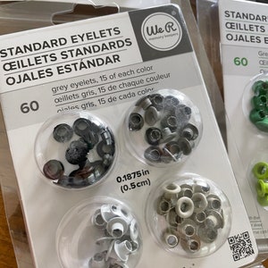 May include: Package of 60 standard eyelets in grey and white, 15 of each color. The eyelets are 0.1875 inches (0.5 cm) in diameter. The package is labeled "Crop-A-Dile" and "We R memory keepers".