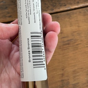May include: A roll of bronze metallic transfer foil in a clear plastic tube with a white label. The label has the text "Bronze Bronze" and a barcode. The label also includes the text "Acid-free Sans acide Sin &aacute;cido", "Assembled in the USA Assembl&eacute;s aux &Eacute;tates-Unis", "Montado en los EE.UU", "Manufactured By Fabriqu&eacute; par Fabricado por Therm O Web, Inc.", "3770 Glenn Ave. Wheeling, IL 60090 www.thermoweb.com".