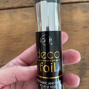 May include: A roll of silver deco foil for crafting. The label reads "iCraft deco foil" and "For fabric and paper, Pour le tissu et le papier, Para la tela y papel".