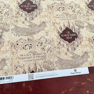 May include: A vintage-style wrapping paper featuring a map with the text "The Marauders Map" and "Messrs Moony, Wormtail, Padfoot & Prongs are proud to present". The paper has a brown and white color scheme with a distressed look.