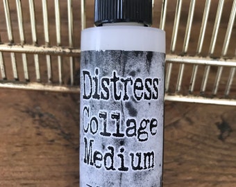 May include: A white bottle of Distress Collage Medium Matte, a 2 fl oz (59 ml) bottle of decoupage medium for mixed media and craft projects.