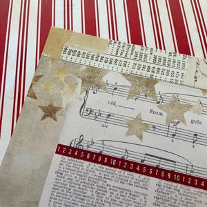 May include: A collage of vintage paper elements with star-shaped embellishments. The design includes sheet music, dictionary pages, and a red and white striped background. A decorative craft project.