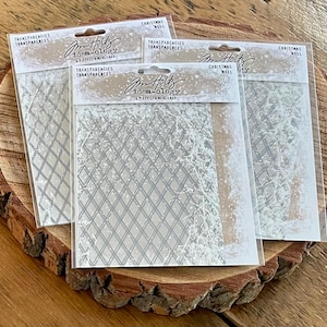 May include: Four packages of clear transparencies with a diamond grid pattern and a snowy design. The packages are labeled "idea-ology" and "Christmas Noel". The transparencies are displayed on a wooden slice.