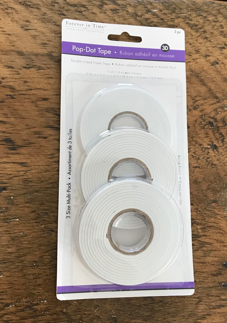 May include: A package of three rolls of double-sided foam tape. The tape is white and comes in three different sizes. The package is labeled "Pop-Dot Tape" and "Ruban adh&eacute;sif en mousse".