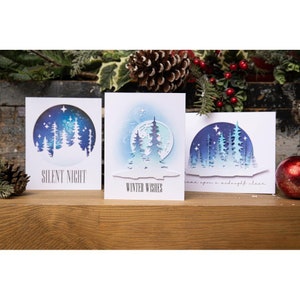 May include: Three white cards with blue and white winter scenes. The cards feature a moon, stars, and trees. The text on the cards reads "Silent Night", "Winter Wishes", and "Once upon a midnight clear".