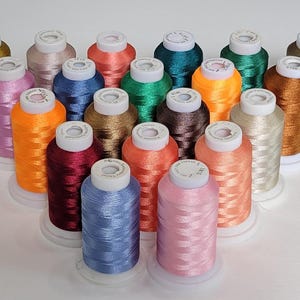 May include: A white ceramic mug with a black handle and the text "But First, Coffee" in a bold, black font. The mug is set against a blurred background, suggesting a cozy setting.