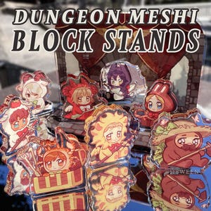 May include: A collection of acrylic block stands featuring anime-style characters in various costumes. The stands are clear with colorful illustrations, including characters dressed as a sheep, crab, and sun. The text "DUNGEON MESHI BLOCK STANDS" is at the top.