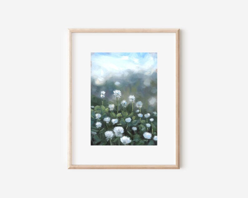 以下が含まれることがあります： 白い花と緑の葉が茂る野原を描いた額装された絵画。花は前景にあり、背景はぼやけた青い空です。