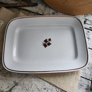 May include: White rectangular serving platter with a brown floral design in the center and a thin gold rim.