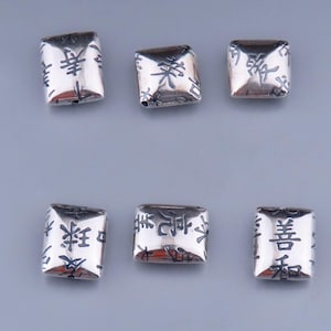May include: Six silver-colored, rectangular beads. Each bead has Chinese characters etched into the surface. The beads are arranged in two rows of three against a neutral background. The beads have a slightly rounded shape.