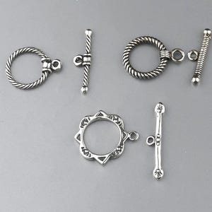 May include: A white ceramic mug with a black handle and the text "But First, Coffee" in a black, bold font. The mug is sitting on a wooden surface. The mug is approximately 4 inches tall.