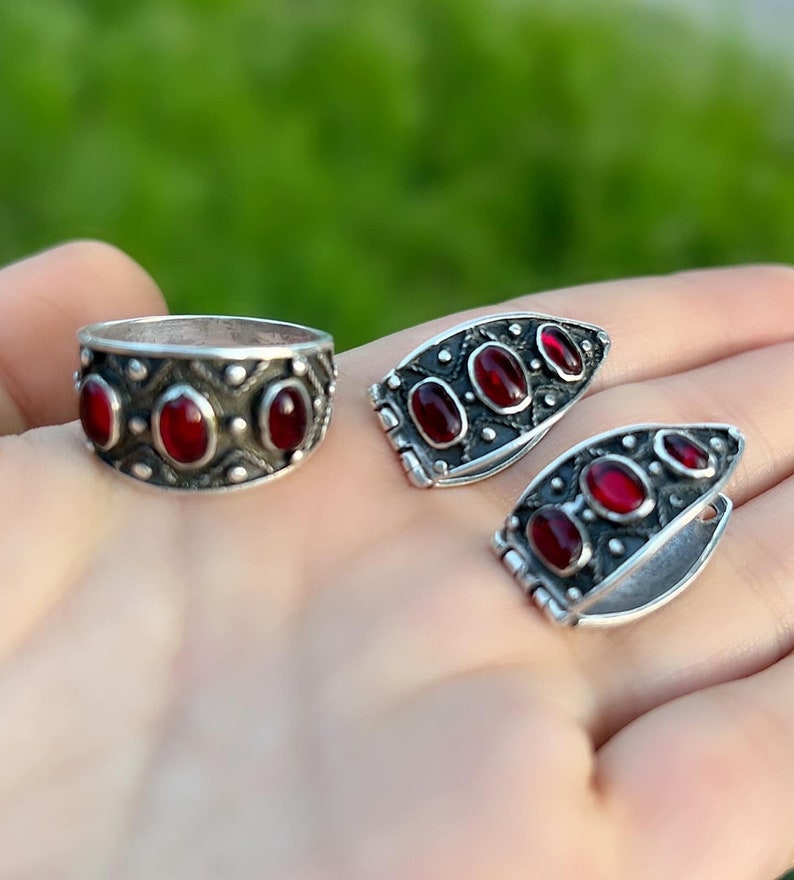 Op de afbeelding: Een set zilveren ringen met rode edelsteen accenten. De ringen hebben een geometrisch ontwerp en zijn bezet met ovale stenen.