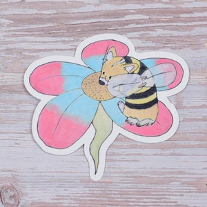 May include: A sticker featuring a cartoon bee with a yellow and black striped body, wearing a flower as a hat. The flower is pink, blue, and white.