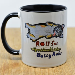 May include: White ceramic coffee mug with a black handle and black rim. The mug features a cartoon illustration of a dog lying on its back with its tongue sticking out. The text "Roll for Initiative Belly Rubs" is printed below the dog.