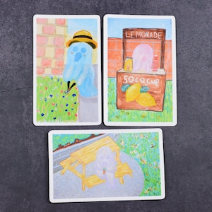 May include: Three illustrated cards with a ghost wearing a yellow hat, a lemonade stand with lemons and a picnic table with a ghost.