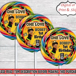 Puede incluir: Tres pegatinas redondas para piruletas con un diseño de espiral de arcoíris. Cada pegatina presenta un círculo negro y amarillo con el texto "One Love Bobby's 1st Birthday" y una ilustración de dibujos animados de un niño pequeño con una corona y un atuendo negro y amarillo.