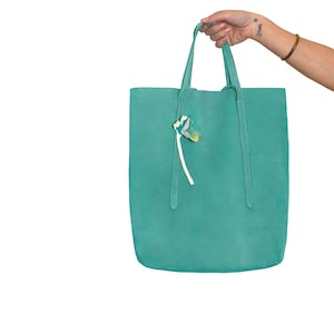 以下が含まれることがあります： 白と黄色の花のチャームが付いたターコイズブルーのトートバッグ