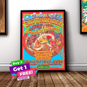 May include: Framed vintage poster for Big Thunder Mountain Railroad at Walt Disney World. The colourful artwork features a train, mountains, and the text "Frontierland." The poster is framed in black and displayed on a wooden floor.