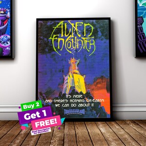 May include: A framed poster with the words "Alien Encounter" in neon green lettering. The poster features a futuristic structure in yellow and white against a purple and blue background. The text "It's here and there's nothing on earth we can do about it" is also visible.