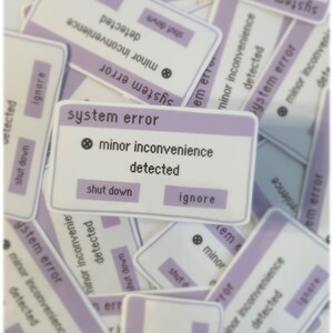 Puede incluir: Un conjunto de pegatinas moradas y blancas con el texto "error del sistema" y "inconveniente menor detectado". Las pegatinas tienen botones que dicen "apagar" e "ignorar".