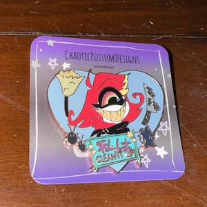 May include: Enamel pin featuring a cartoon character with red hair, a wide grin, and a black suit. The pin includes a broom, a knife, and the Japanese text "I will clean it up!" on a sign. The pin is on a purple backing.