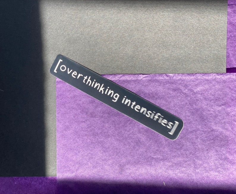 May include: A silver sticker with the text "[overthinking intensifies]" on a purple background.