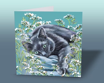 Può includere: Biglietto di auguri con un gatto grigio con occhi verdi, appoggiato tra fiori bianchi e steli verdi. Il gatto è sdraiato su una superficie blu, con uno sfondo turchese. Il biglietto è piegato e ha un interno bianco.