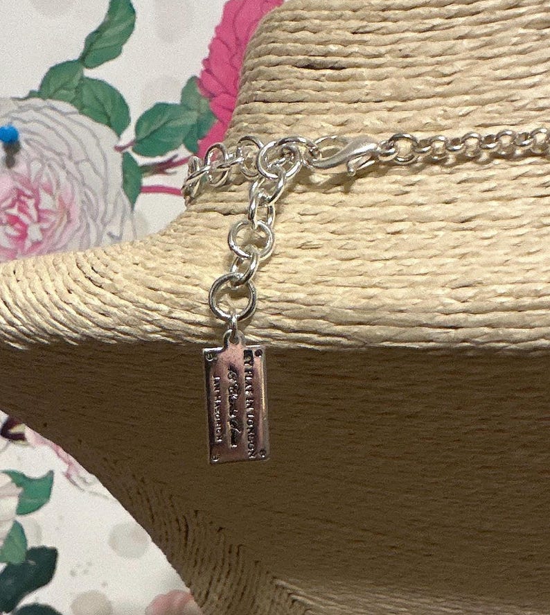May include: Silver-toned necklace with a lobster clasp and a small rectangular tag. The tag has engraved text that reads "MY PLACE IN LONDON" and other text. The necklace is displayed on a tan mannequin head.