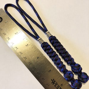 May include: Two black and blue paracord keychains with silver beads. The keychains are approximately 5 inches long and are measured against a ruler.