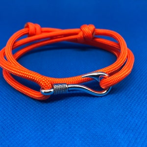May include: Orange paracord bracelet with a silver hook clasp.