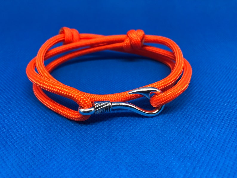 May include: Orange paracord bracelet with a silver hook clasp.