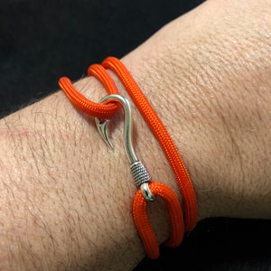 May include: A bright orange paracord bracelet with a silver hook clasp.