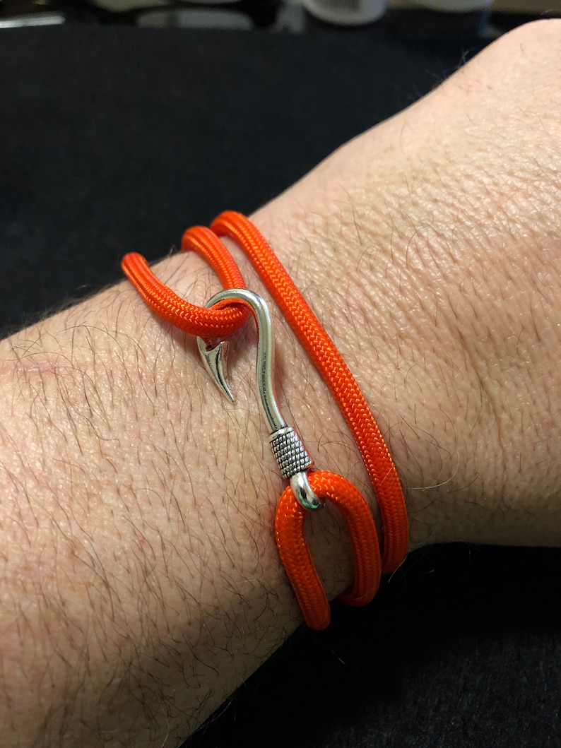 May include: A bright orange paracord bracelet with a silver hook clasp.