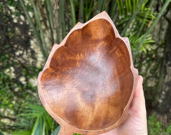May include: A wooden bowl shaped like a leaf, with a dark brown color and a smooth, polished finish.
