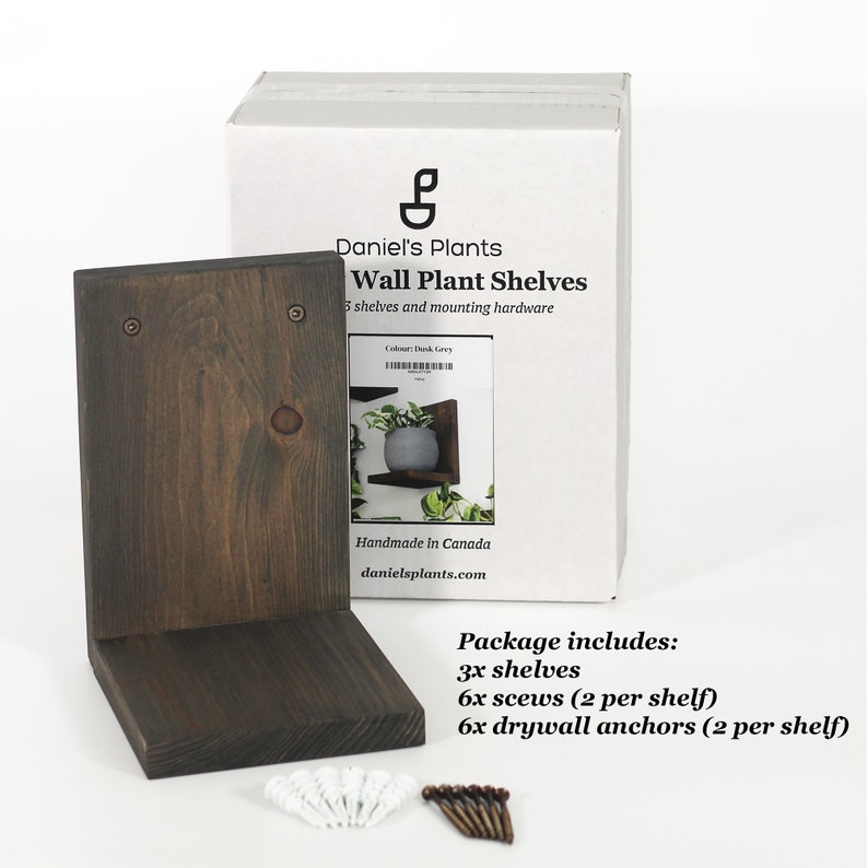 May include: Dark grey wooden wall plant shelf with a matching box labeled "Daniel's Plants Wall Plant Shelves." The box includes the text "Handmade in Canada." The package includes 3 shelves, 6 screws, and 6 drywall anchors.