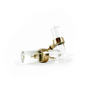 May include: Two clear glass cabinet knobs with gold metal accents. The knobs are shaped like short cylinders with a rounded end.