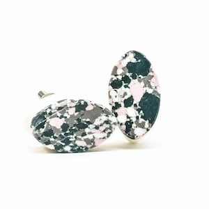 Op de afbeelding: Twee ovale kastknoppen met een witte basis en een marmerpatroon in roze, zwart en grijs.