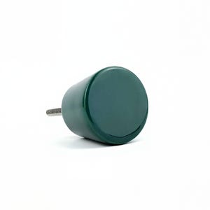 May include: A dark green cylindrical cabinet knob with a threaded metal screw extending from one end. The knob has a smooth, glossy finish and a flat, circular face. The hardware is designed for use on drawers or cabinet doors.