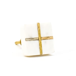 May include: White square cabinet knob with a gold and brown cross inlay.