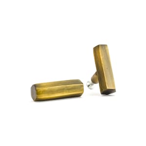 May include: Two antique brass cabinet knobs with a hexagonal shape. The knobs have a brushed finish and are designed for use on furniture.
