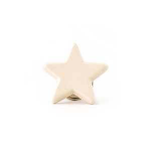 May include: A beige ceramic star-shaped knob with a silver metal base.