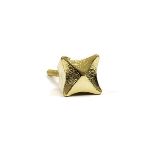 May include: A gold-toned metal knob with a star-shaped design. The knob has a pointed top and a short, cylindrical stem.