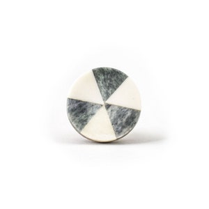 Könnte beinhalten: Runder, weißer und grauer Marmorknopf mit geometrischem Muster.