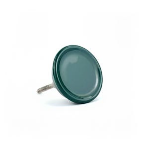 May include: A dark green cabinet knob with a round, glossy face and a threaded metal screw. The knob is a solid colour and appears to be made of ceramic or a similar material. The hardware is designed for furniture.
