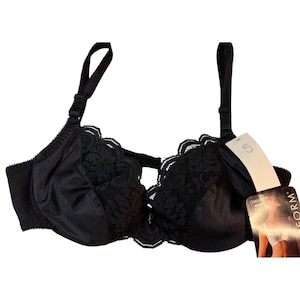 May include: Black bra with adjustable straps and lace detailing along the cups. The bra has a tag attached with the number 5. The bra is made of a smooth, shiny material.