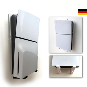 Könnte beinhalten: Weiße Wandhalterung für eine PlayStation 5 Konsole. Die Halterung ist aus weißem Kunststoff und hat ein schlichtes Design. Die Konsole ist nicht im Lieferumfang enthalten.